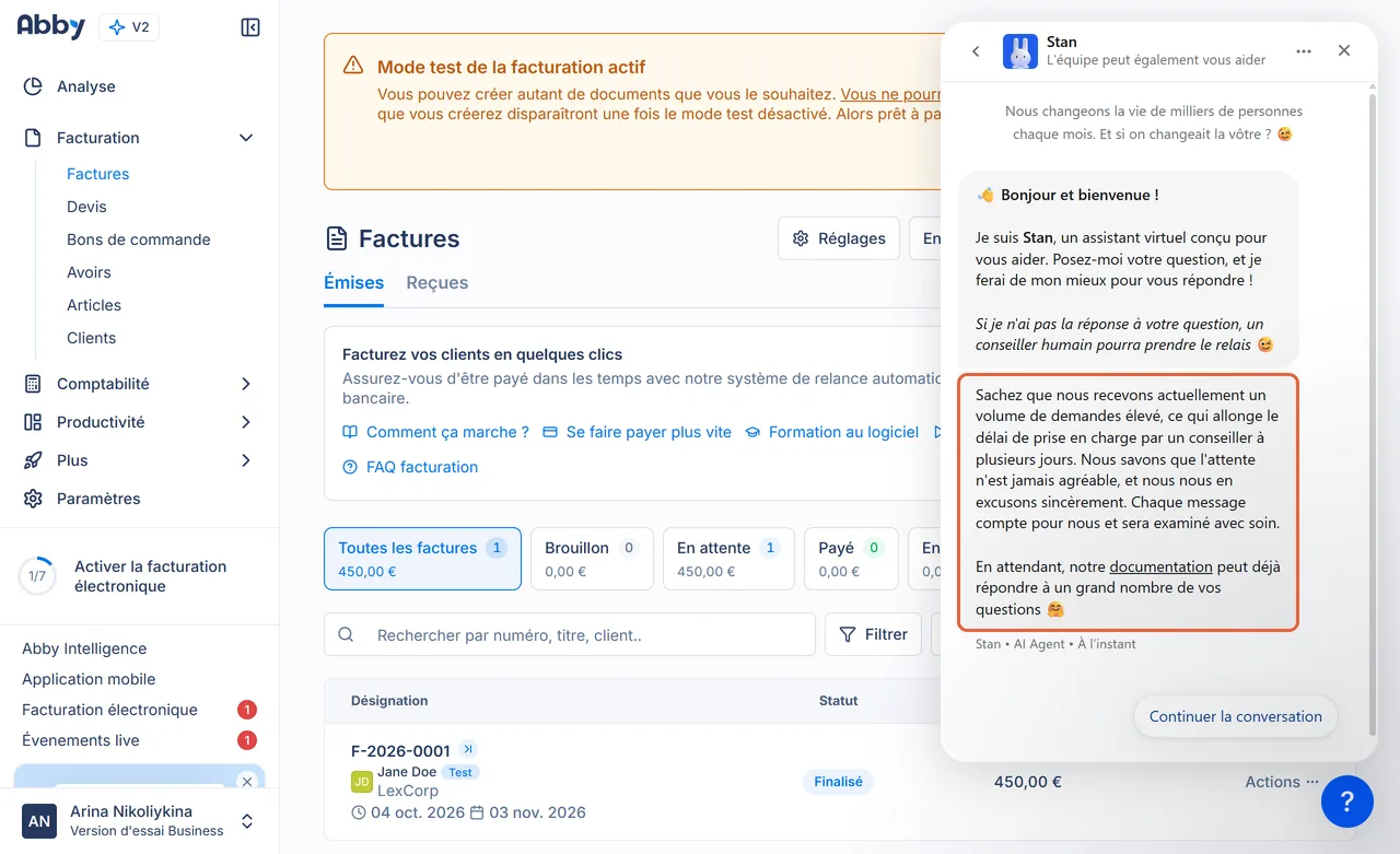 Chat d'Abby à l'ouverture : l'assistant IA Stan se présente, puis le message encadré annonce un volume de demandes élevé qui allonge le délai de prise en charge par un conseiller à plusieurs jours